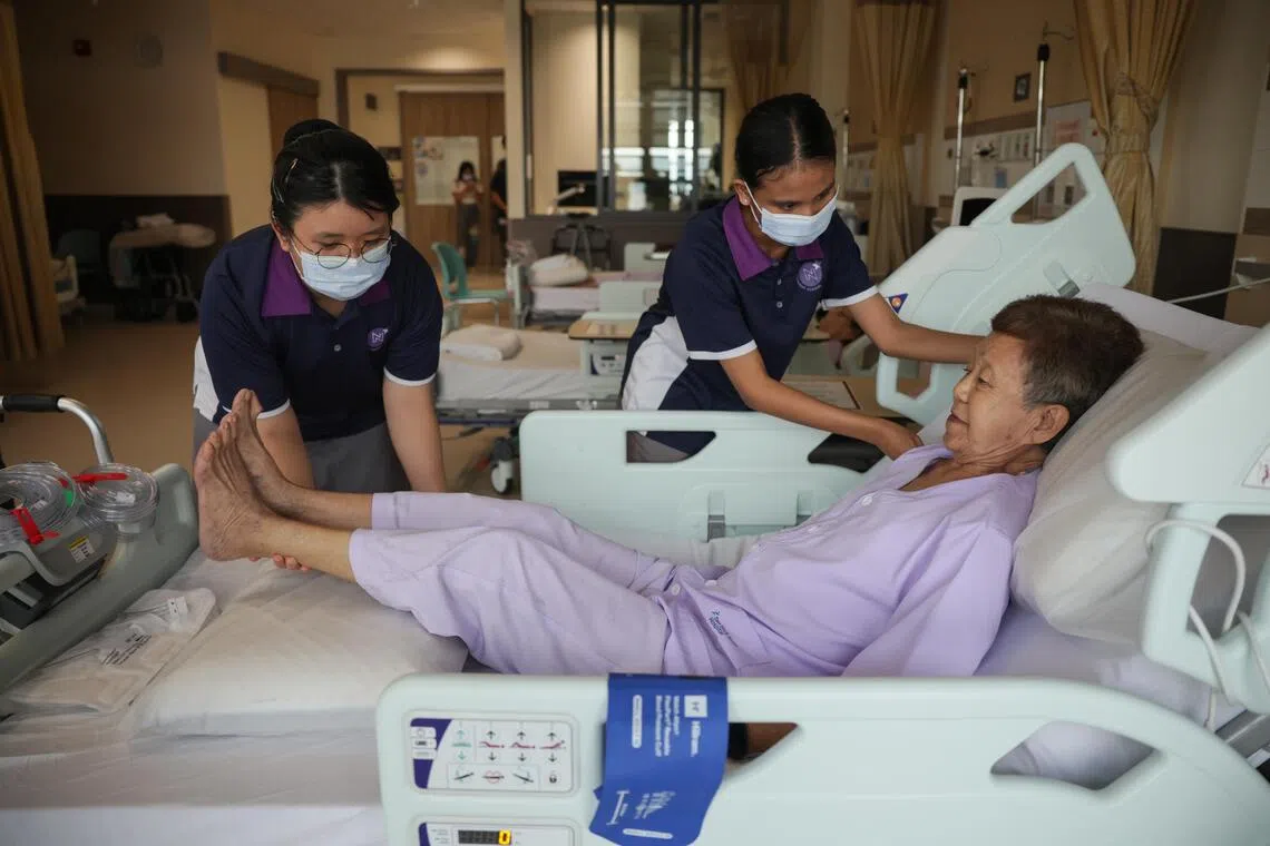 NorthLight School students Esther Kuan Yi Lin (left) and Puteri Ellysha Misram tending to a patient during a demonstration at the orthopaedic and general surgical ward in the TTSH Integrated Care Hub on June 30.