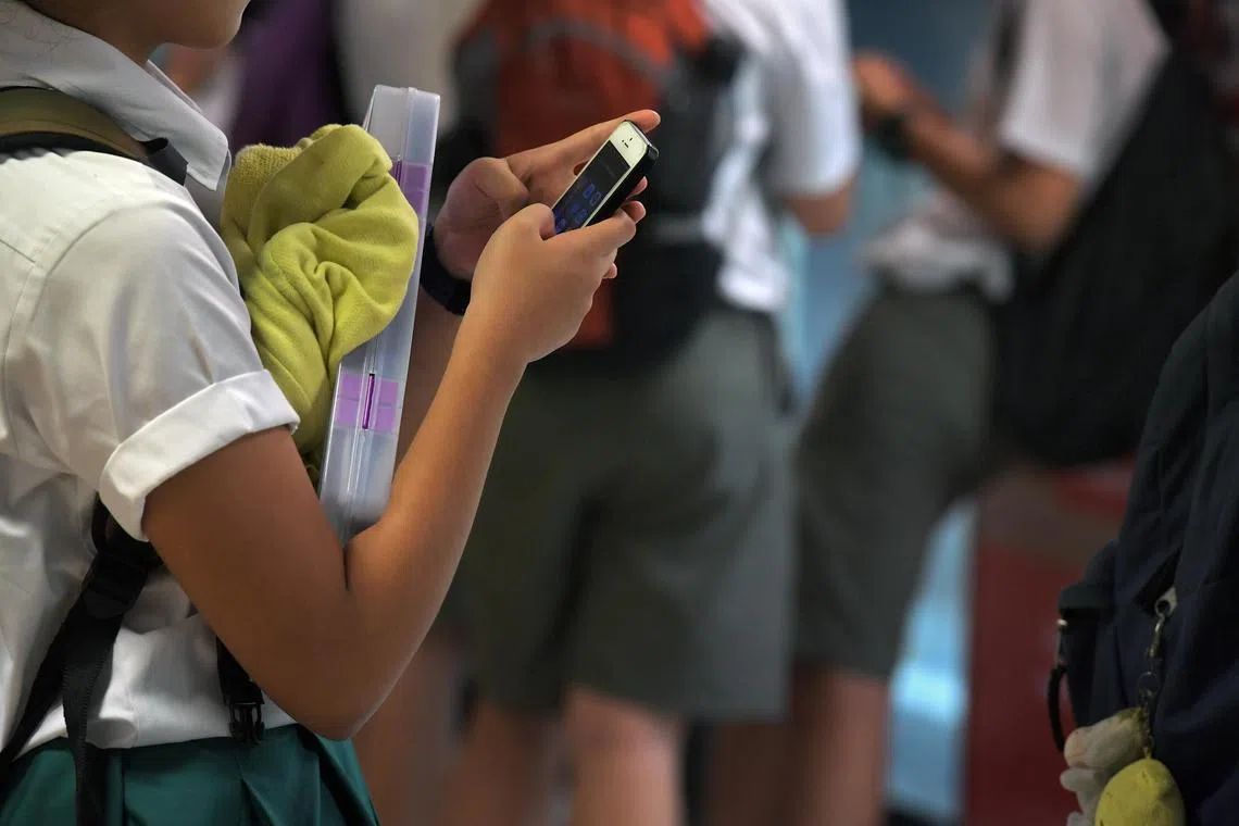 Students using their mobile phones at Bishan MRT station on 23 February 2017.