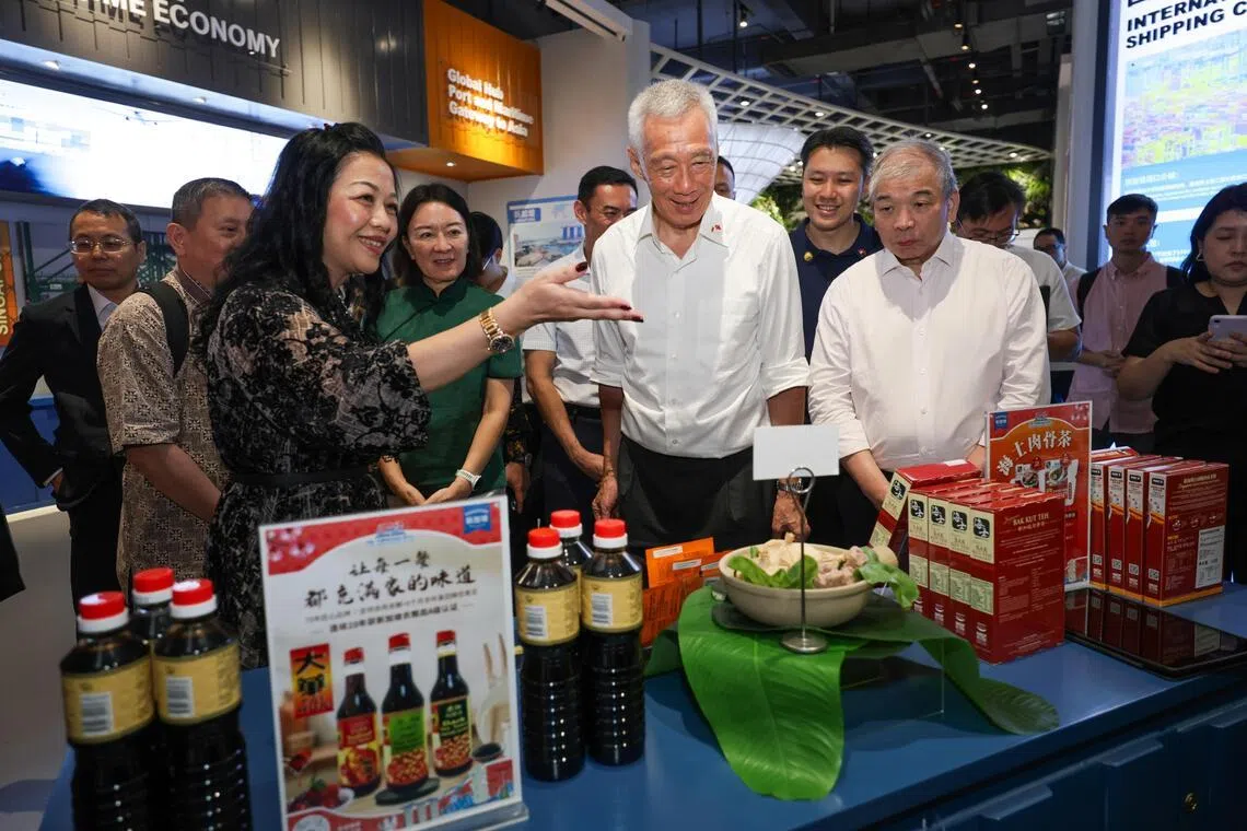 (Second from left): Peter Tan, Ambassador of Singapore to the People's Republic of China (partially blocked); China-ASEAN Mercantile Exchange president Bebe Zhao; Guangxi Vice Chairwoman Lu Xinning; Member of Parliament for Jalan Besar GRC Dr Wan Rizal (partially blocked); Senior Minister Lee Hsien Loong; Senior Parliamentary Secretary in the Ministry of Finance and the Ministry of Manpower Shawn Huang; and Teo Siong Seng, chairman of China-Singapore Nanning International Logistics Park (CSILP); touring Singapore pavilion at China - ASEAN Mercantile Exchange in Nanning Guangxi on May 19, 2026.
