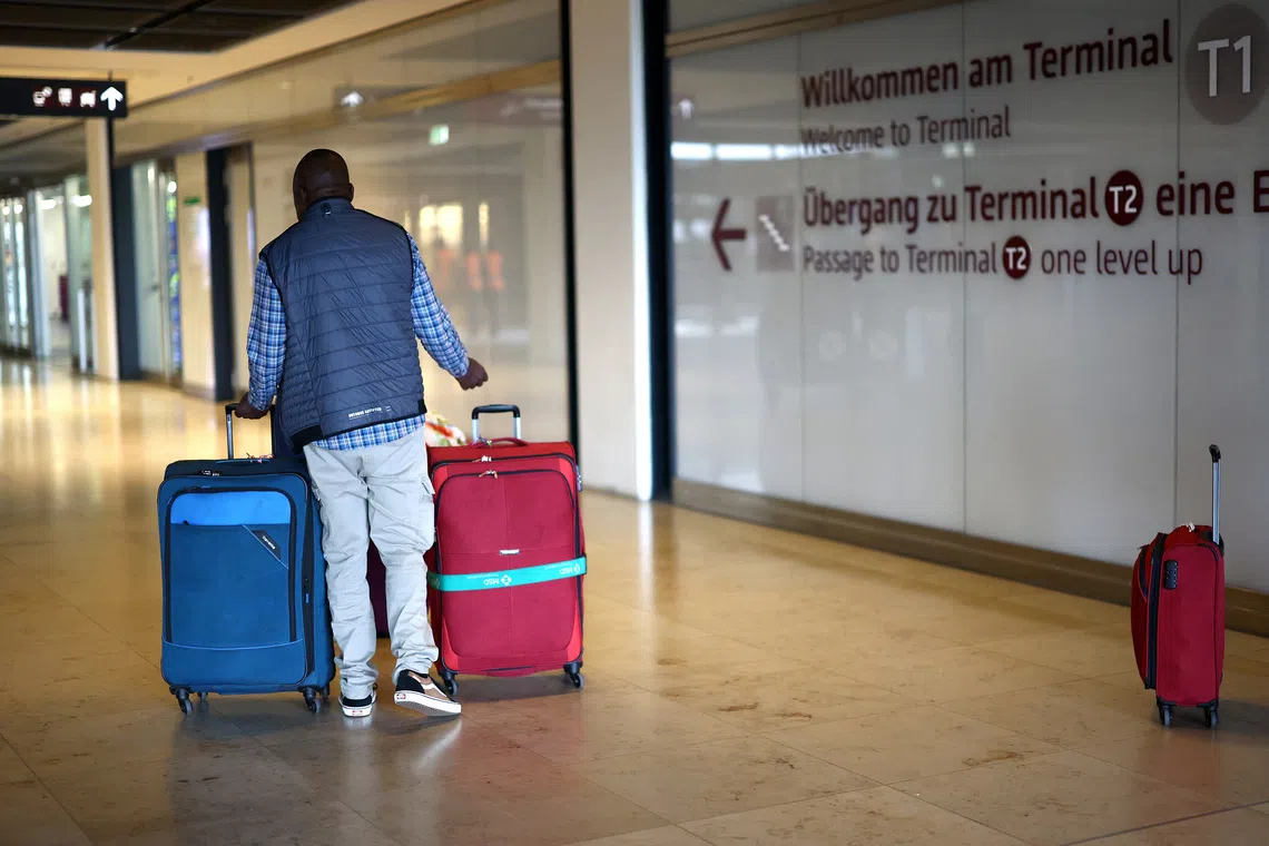 FILE PHOTO: A man wheels luggage at the entrance of Berlin Brandenburg Airport in Schoenefeld, Germany, July 17, 2025. REUTERS/Lisi Niesner/File Photo