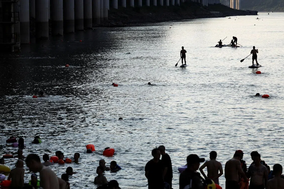 People ride paddle boards on the Jialing River amid a red alert for heat in Chongqing, China July 31, 2025. REUTERS/Go Nakamura