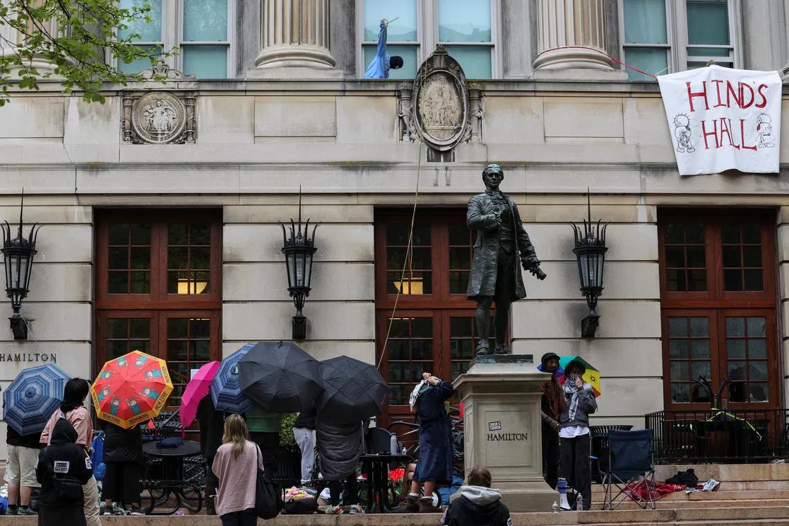 Protesters hold umbrellas as they move supplies into Hamilton Hall, where students at Columbia University have barricaded themselves inside as they continue to protest in support of Palestinians, despite orders from university officials to disband, or face suspension, during the ongoing conflict between Israel and the Palestinian Islamist group Hamas, in New York City, U.S., April 30, 2024. REUTERS/Caitlin Ochs