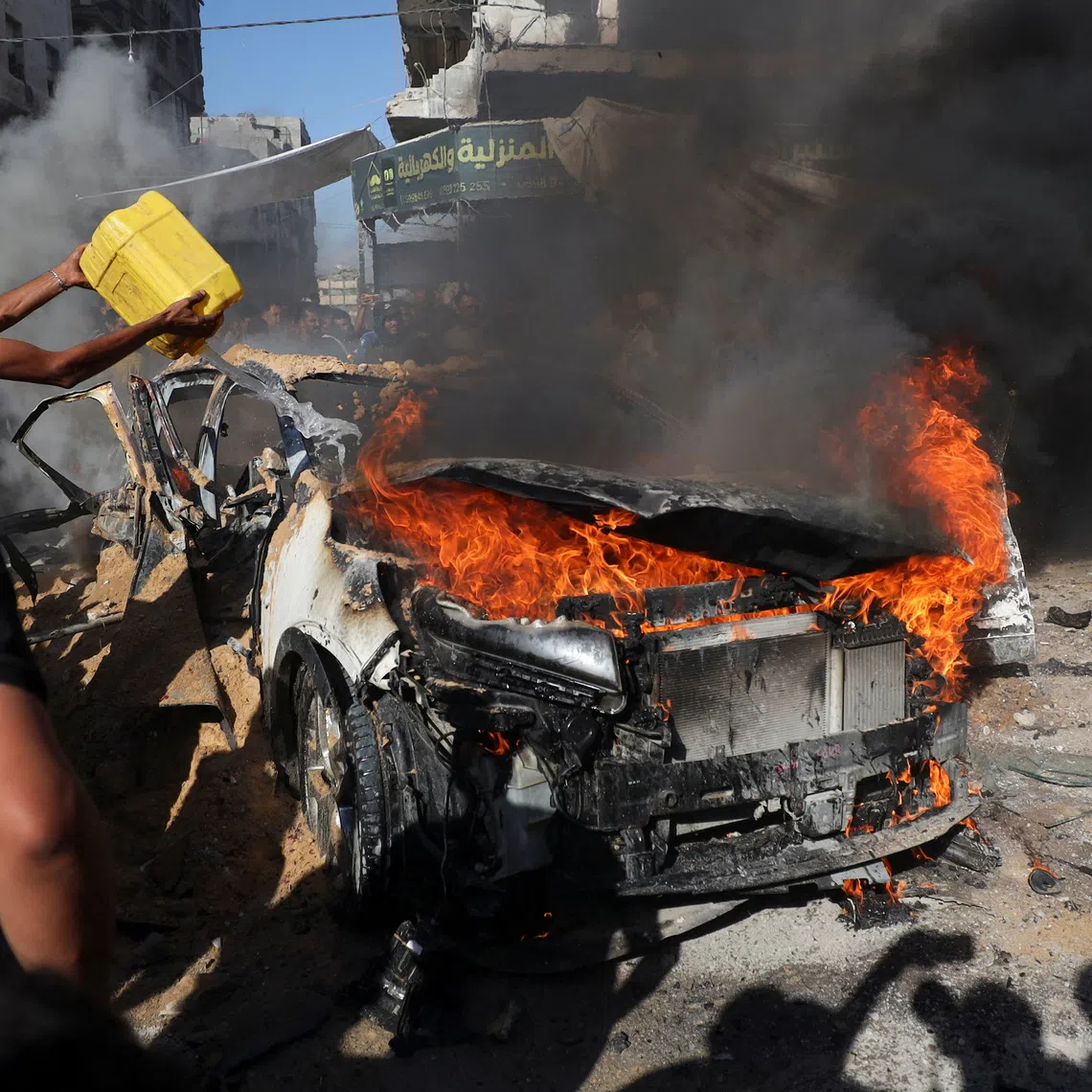 Palestinians attempting to extinguish a fire following an Israeli air strike that hit a vehicle in Gaza City on Sept 19.
