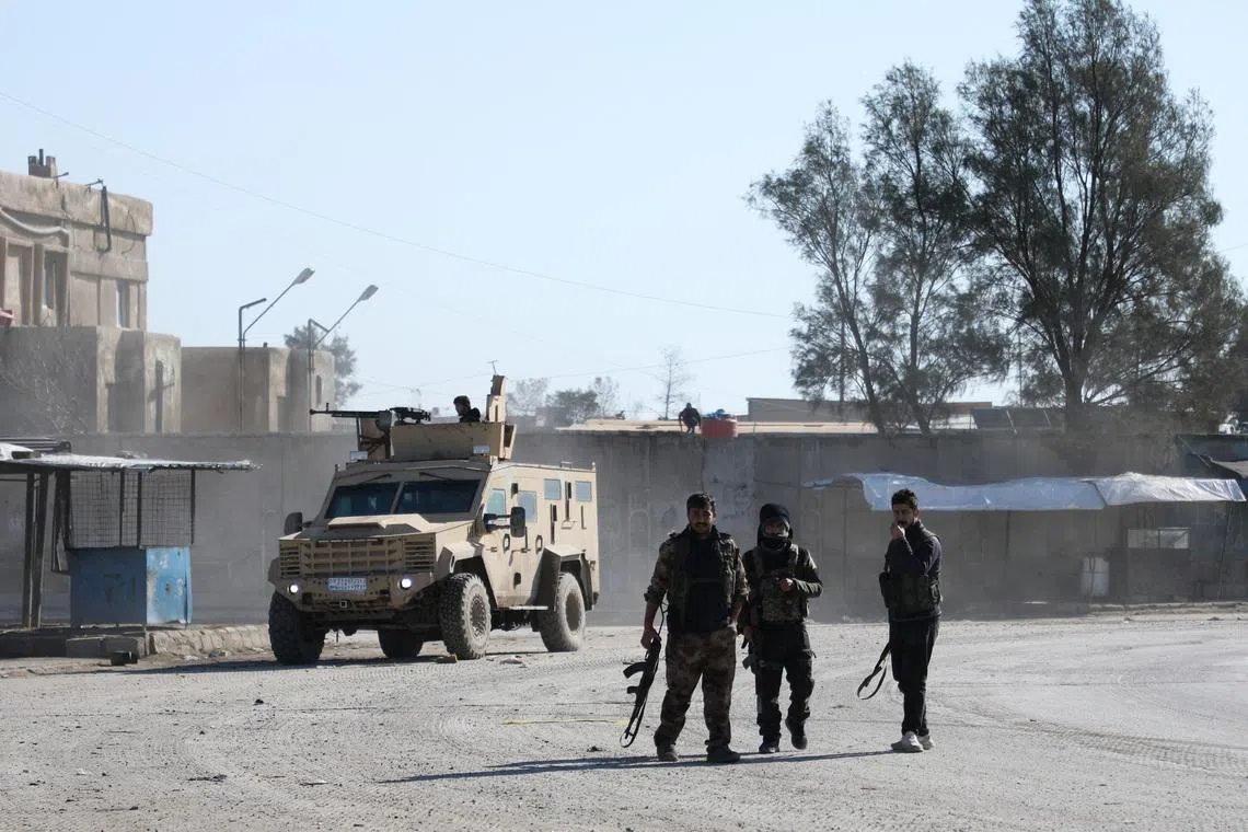 Syrian Democratic Forces (SDF) fighters walk near an armored vehicle, following clashes between SDF and Syrian government forces, in Hasakah, Syria, January 20, 2026. REUTERS/Orhan Qereman