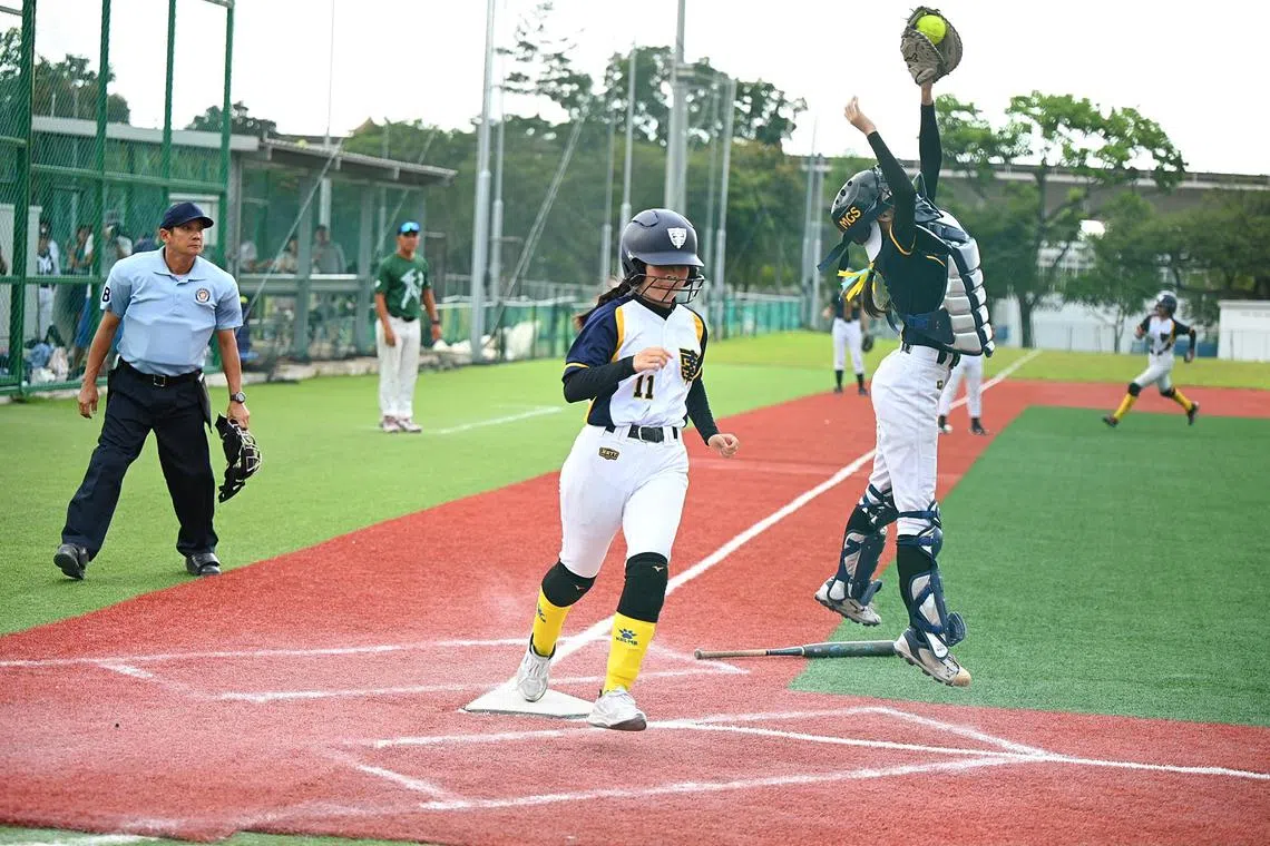 Nanyang Girls' Kaylene Chan scored a home run against MGS catcher, Natalie Chng during the C Division softball final at Jurong East Softball field on 23 August 2024.