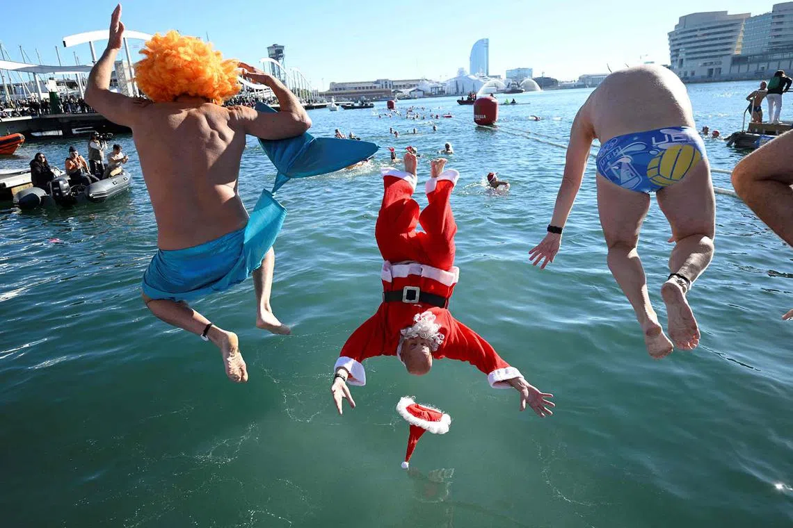 Participants in fancy costumes jumping into the water during the 114th edition of the Copa Nadal (Christmas Cup) swimming race in Barcelona's Port Vell on Dec 25, 2023. 