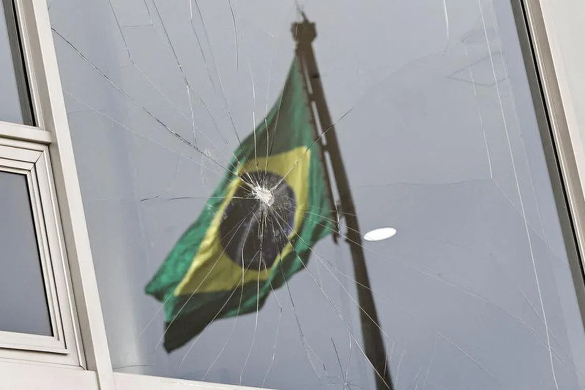 FILE PHOTO: Brazil's flag is reflected on a broken window, after the supporters of Brazil's former President Jair Bolsonaro participated in an anti-democratic riot at Planalto Palace, in Brasilia, Brazil, January 9, 2023. REUTERS/Ueslei Marcelino / File Photo