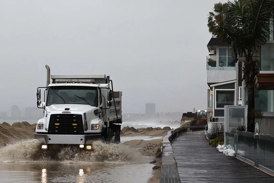 LONG BEACH, CALIFORNIA - FEBRUARY 20: A worker drives through standing water while creating sand berms to protect beachfront homes from flooding on February 20, 2024 in Long Beach, California. Another atmospheric river storm is delivering heavy rains to California two weeks after a powerful storm brought widespread flooding, mudslides and power outages to parts of the state.   Mario Tama/Getty Images/AFP (Photo by MARIO TAMA / GETTY IMAGES NORTH AMERICA / Getty Images via AFP)