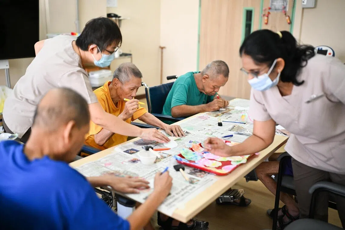 St Andrew's Nursing Home (Buangkok) residents doing cognitive art and craft with therapy assistants Kelly Poh (standing, left) and Rekha Chandran.