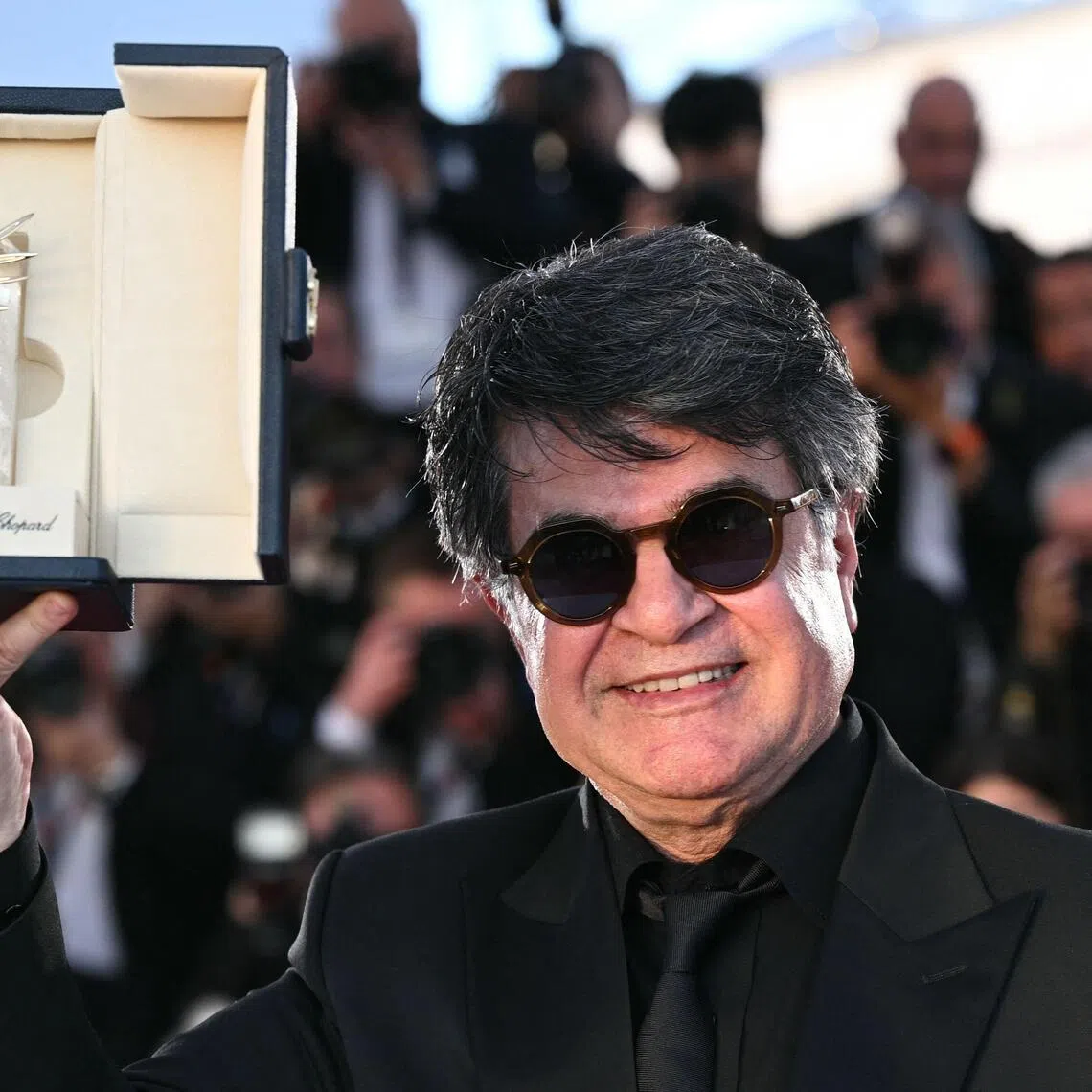 Iranian filmmaker Jafar Panahi shows off the trophy he received after winning the Palme d’Or at the Cannes film festival in 2025.