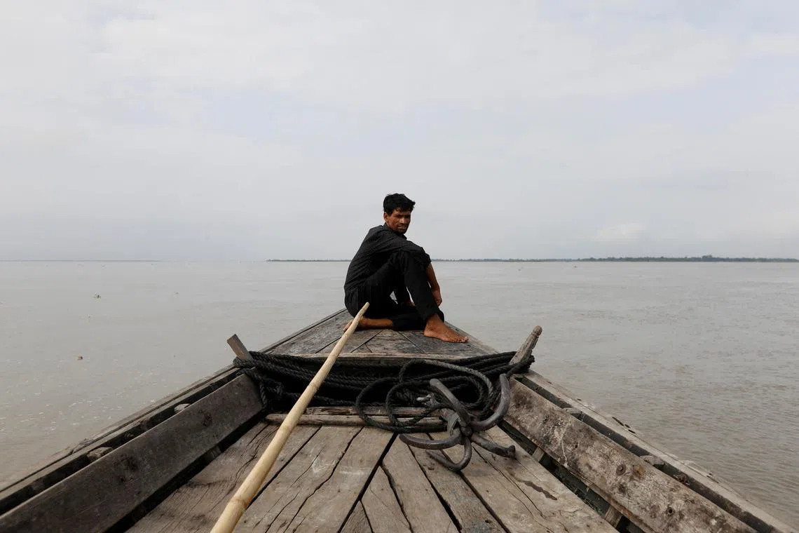 A man sits in a boat on the waters of the Brahmaputra river, where the Yarlung Zangbo flows south. 