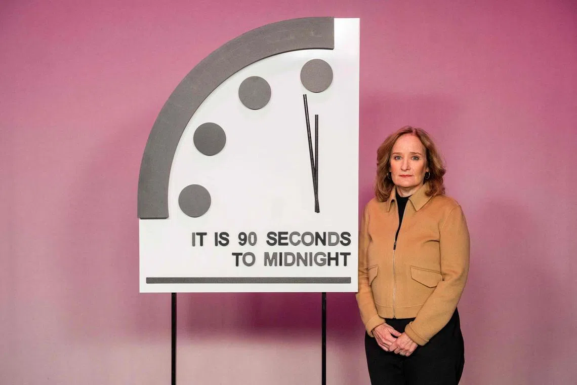 Dr Rachel Bronson stands next to the Doomsday Clock, which warns the public  how close humankind is to destroying the world.