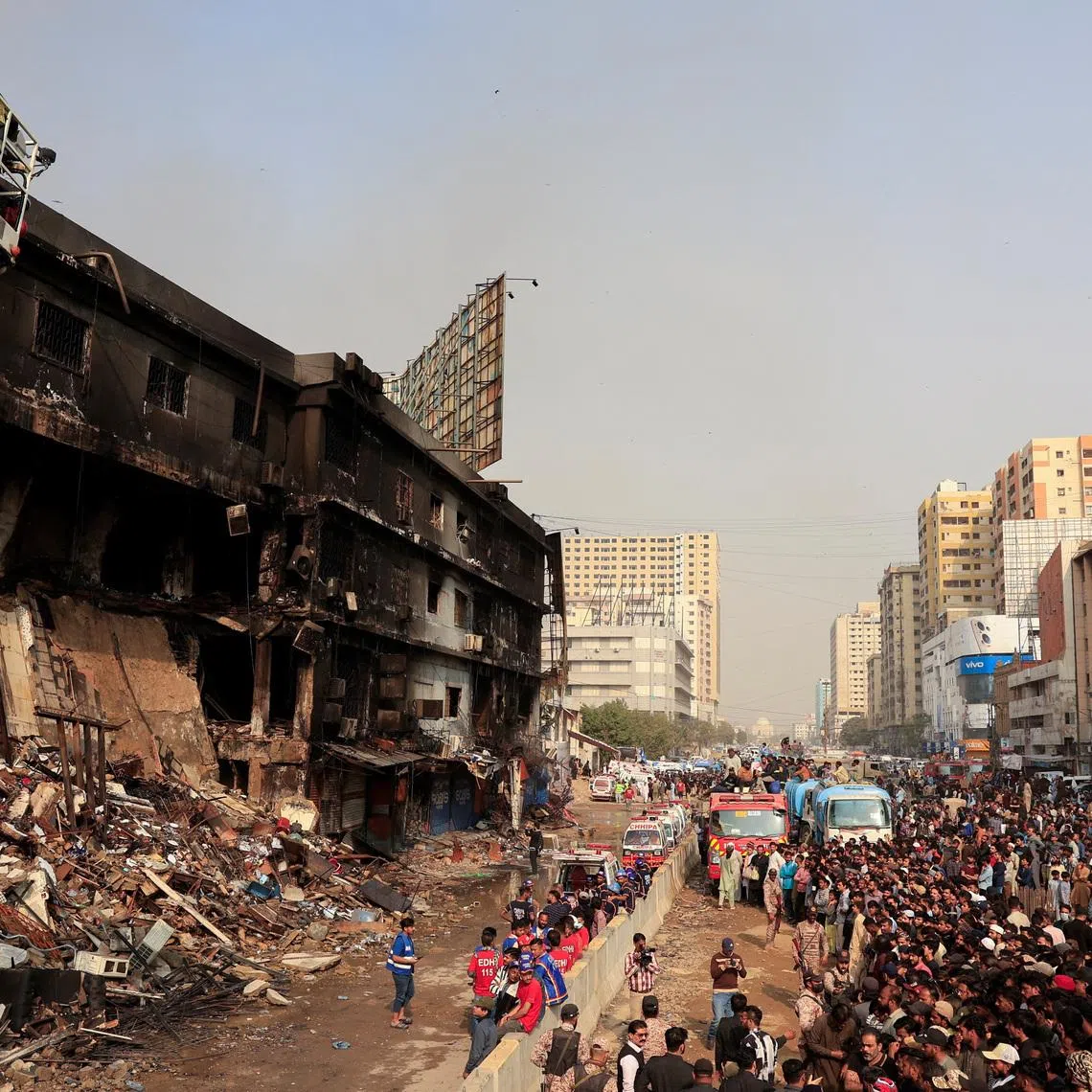 People gather as emergency personnel search for survivors, following a massive fire that broke out in the Gul Plaza Shopping Mall in Karachi, Pakistan, January 19, 2026. REUTERS/Akhtar Soomro