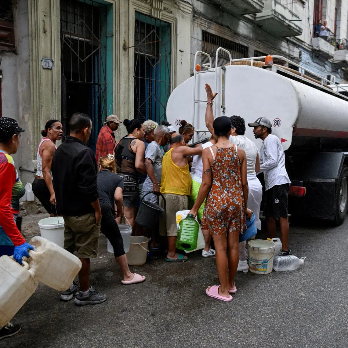 FILE PHOTO: People gather around a water tanker truck to fill up buckets and other containers as severe fuel shortages have disrupted water pumping and distribution, in Havana, Cuba March 19, 2026. REUTERS/Norlys Perez/File Photo
