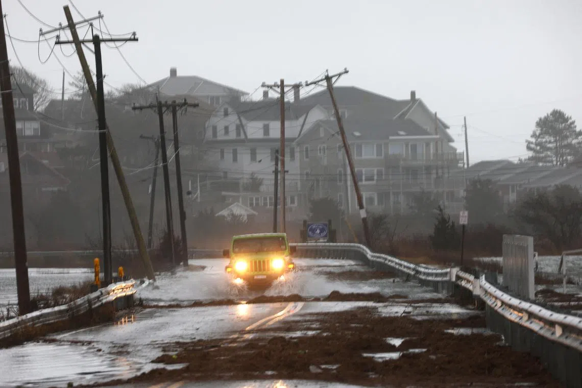 A driver makes their way through a flooded street at high tide during a winter storm in Gloucester, Massachusetts, U.S., December 23, 2022.  