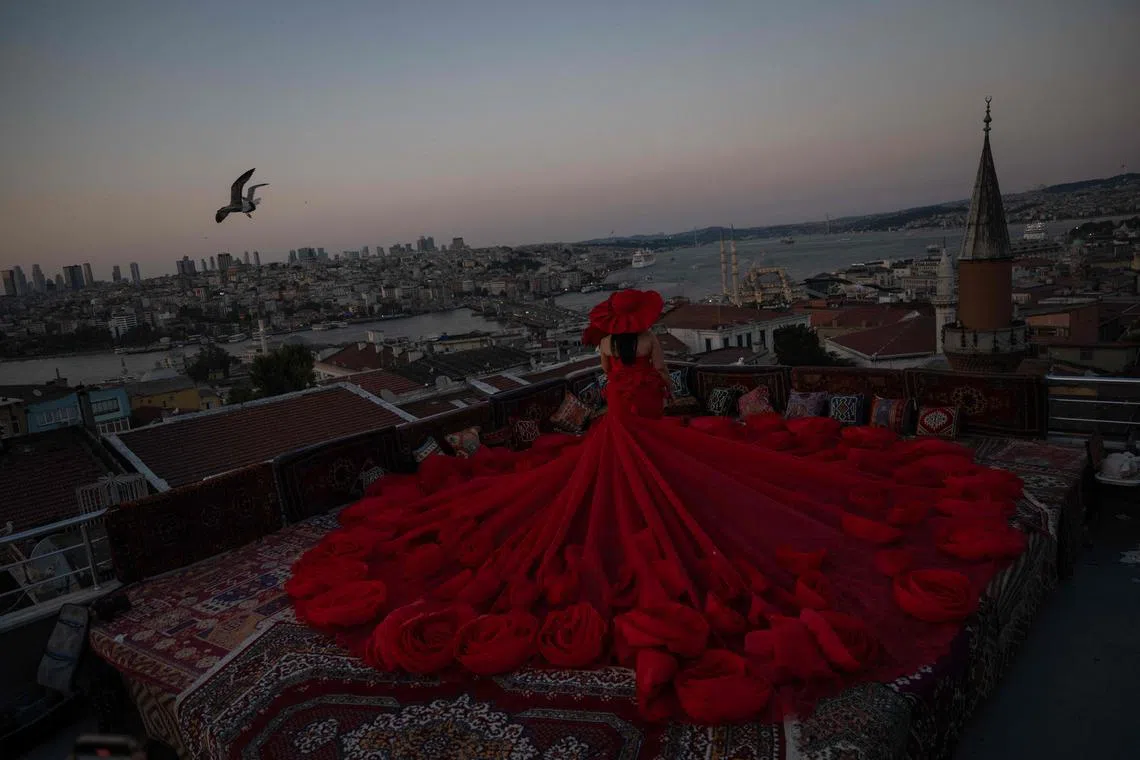 A tourist looking out towards the Bosphorus as they pose for a photo in an open-air studio terrace, in Istanbul, on July 21, 2025. 