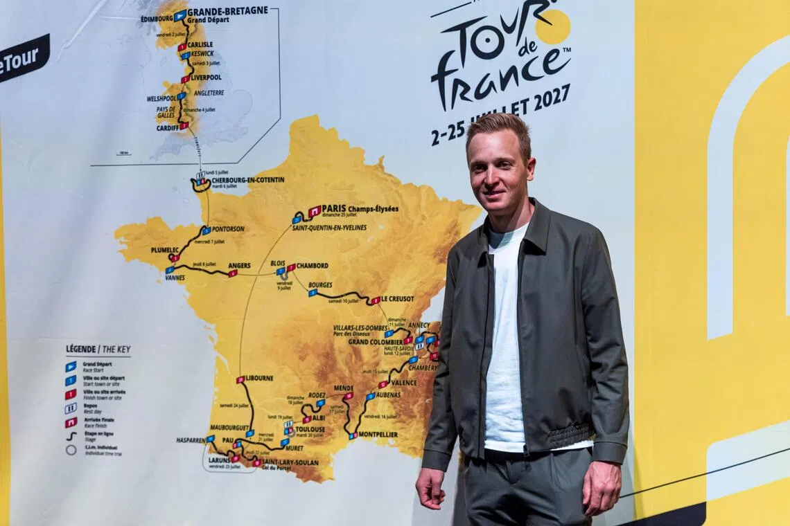 Belgian cyclist Tim Merlier posing for photographs in Paris on Oct 22, next to a map of the stages for the 2027 Tour de France cycling race.