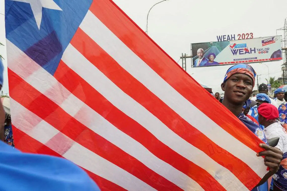 FILE PHOTO: A supporter of the leader of Liberia's ruling party Coalition for Democratic Change (CDC), President and former soccer player George Weah, holds a national flag during Weah's final campaign rally for the presidential elections in Monrovia, Liberia October 8, 2023. REUTERS/Carielle Doe/File Photo