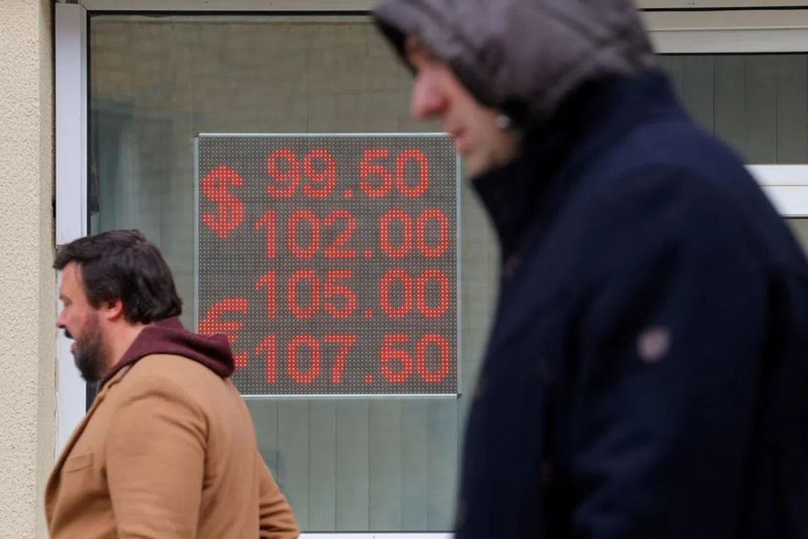 FILE PHOTO: Pedestrians walk past an electronic board showing currency exchange rates of the U.S. dollar and euro against Russian rouble in a street in Moscow, Russia, October 6, 2023. REUTERS/Evgenia Novozhenina/File Photo