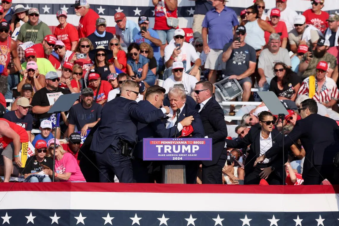 Republican presidential candidate Donald Trump is assisted by US Secret Service personnel after he was shot in the right ear during a campaign rally in Butler, Pennsylvania, on July 13, 2024.