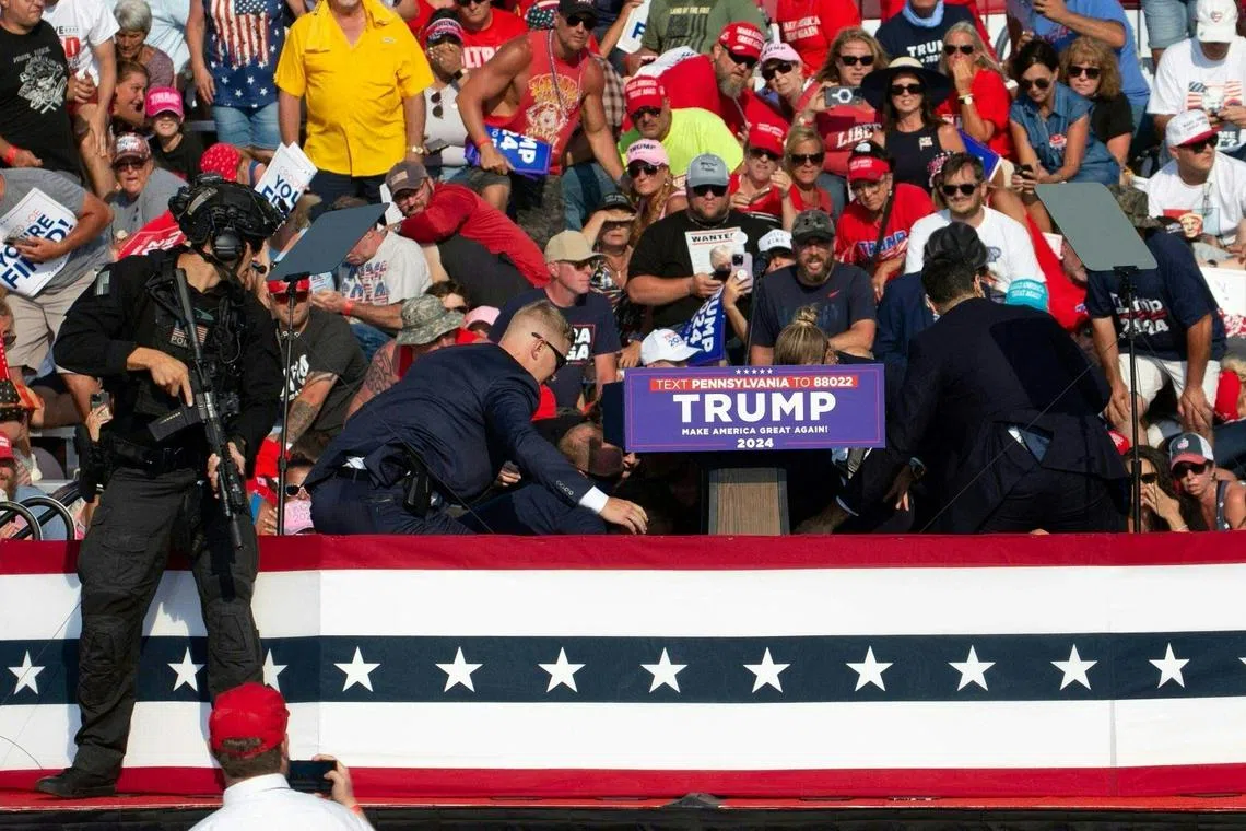 Former US president Donald Trump (hidden) being escorted off the stage by secret service agents after shots were fired at his rally in Pennsylvania.