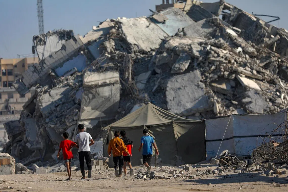 Palestinian children walking next to the rubble of destroyed buildings in Gaza City on Oct 28.