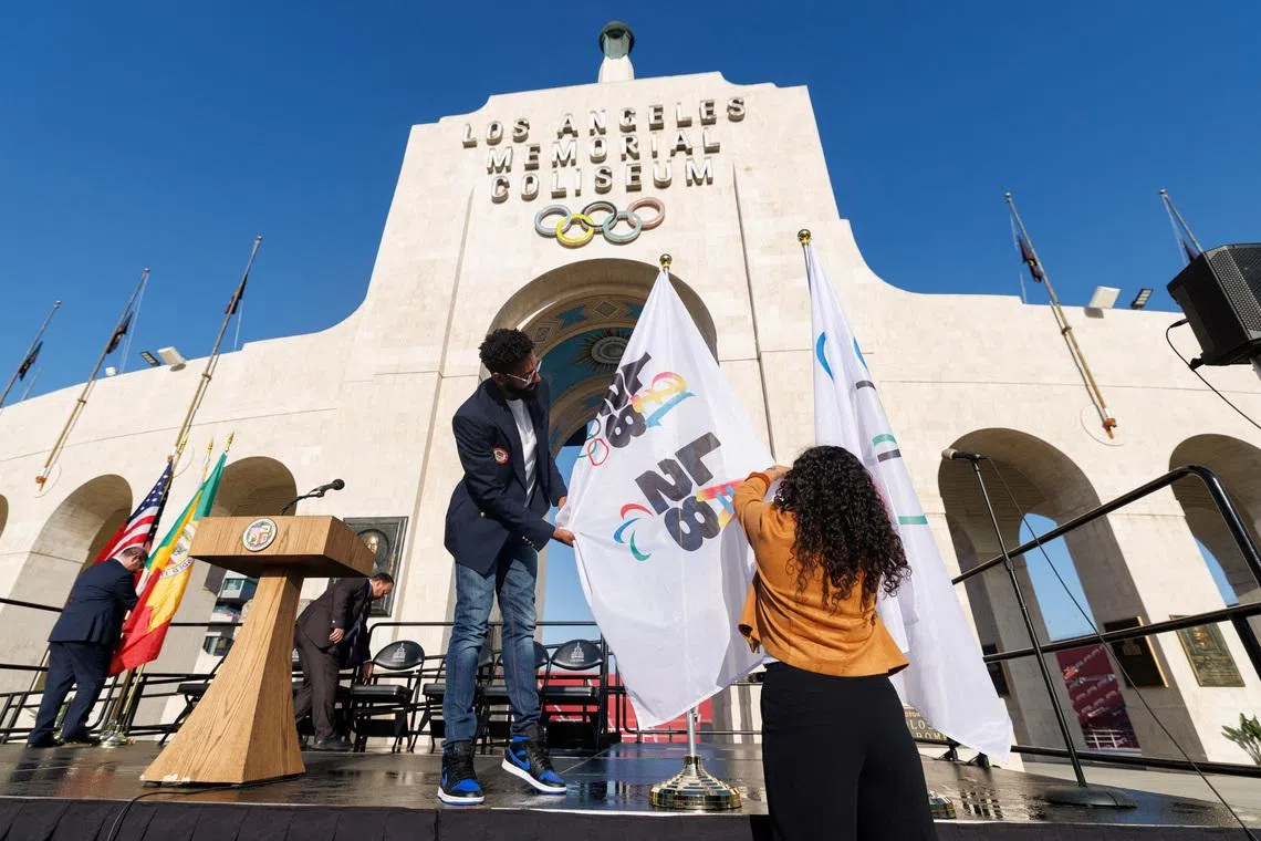 Workers from LA28 setup Olympic and Paralympic flags outside the Los Angeles Coliseum in Los Angeles, California, U.S., May 8, 2025.