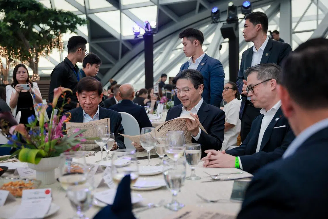 Prime Minister Lawrence Wong looking at a replica copy of the first issue of The Straits Times at ST's 180th anniversary dinner at Jewel Changi Airport on July 11.