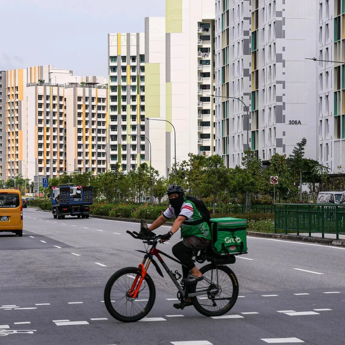 A food delivery rider riding across the road along Tengah Drive, with Parc Flora (left) and Parc Woods (centre) estate in the background, on Dec 26, 2025. ST PHOTO: BRIAN TEO