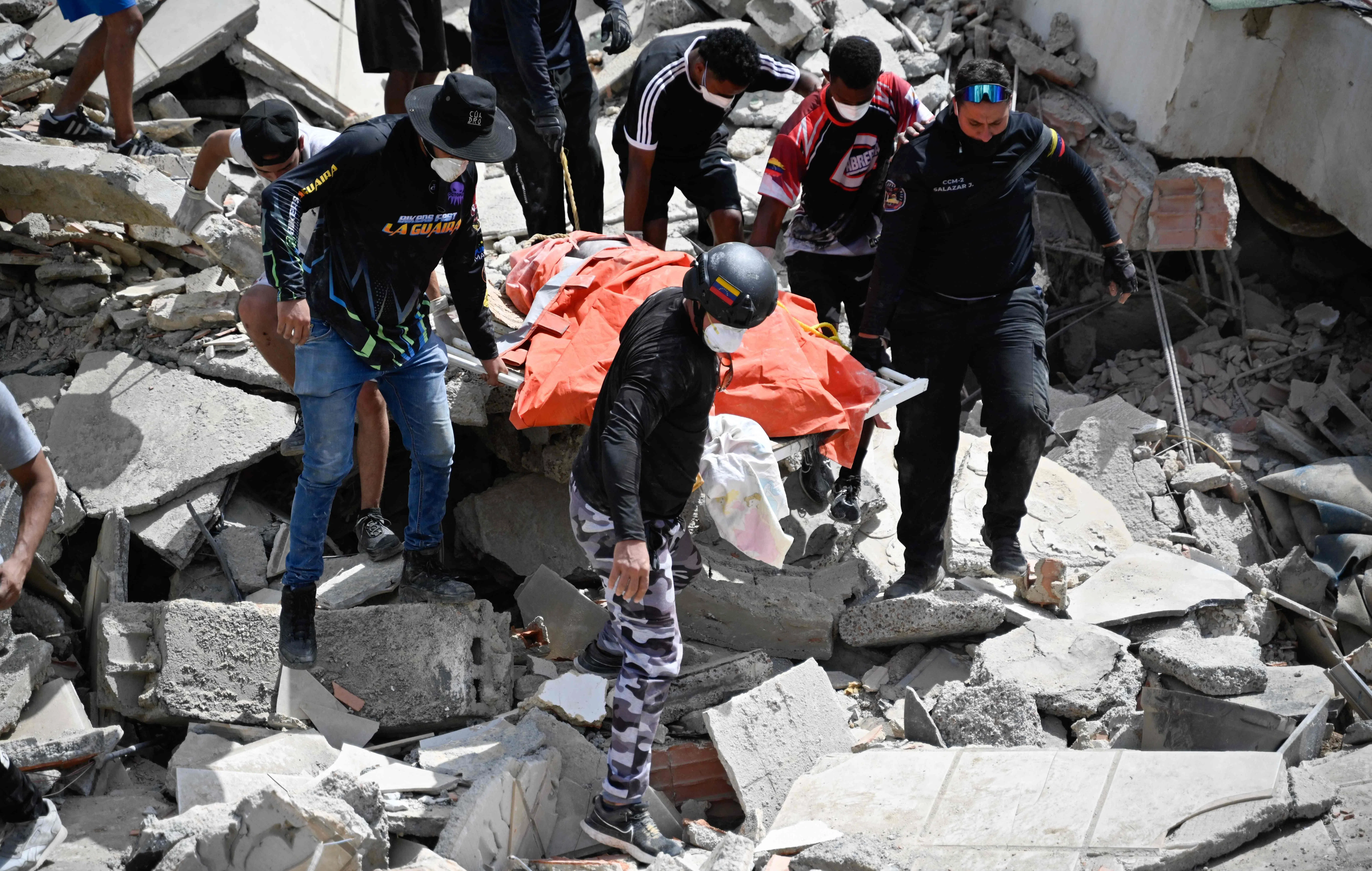 Venezuelan Civil Protection members and volunteers recover a body at the site of collapsed buildings following earthquakes in Caraballeda, La Guaira state, Venezuela, on June 26, 2026. The death toll from two powerful earthquakes that devastated Venezuela earlier this week rose to 920 on June 26, National Assembly President Jorge Rodriguez said. (Photo by Maryorin Mendez / AFP)