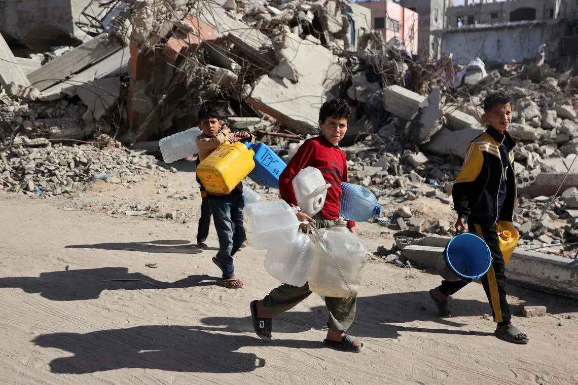Children carry containers, as Palestinians make their way to flee their homes, after the Israeli army issued evacuation orders for a number of neighborhoods, following heavy Israeli strikes, in Beit Hanoun in the northern Gaza Strip March 19, 2025. REUTERS/Abd Elhkeem Khaled