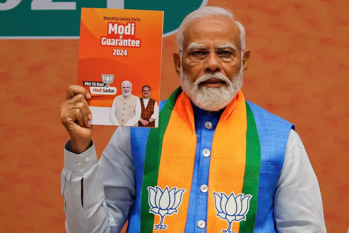Indian Prime Minister Narendra Modi displays a copy of the ruling Bharatiya Janata Party's (BJP) election manifesto for the general election, in New Delhi, India, April 14, 2024. REUTERS/Adnan Abidi