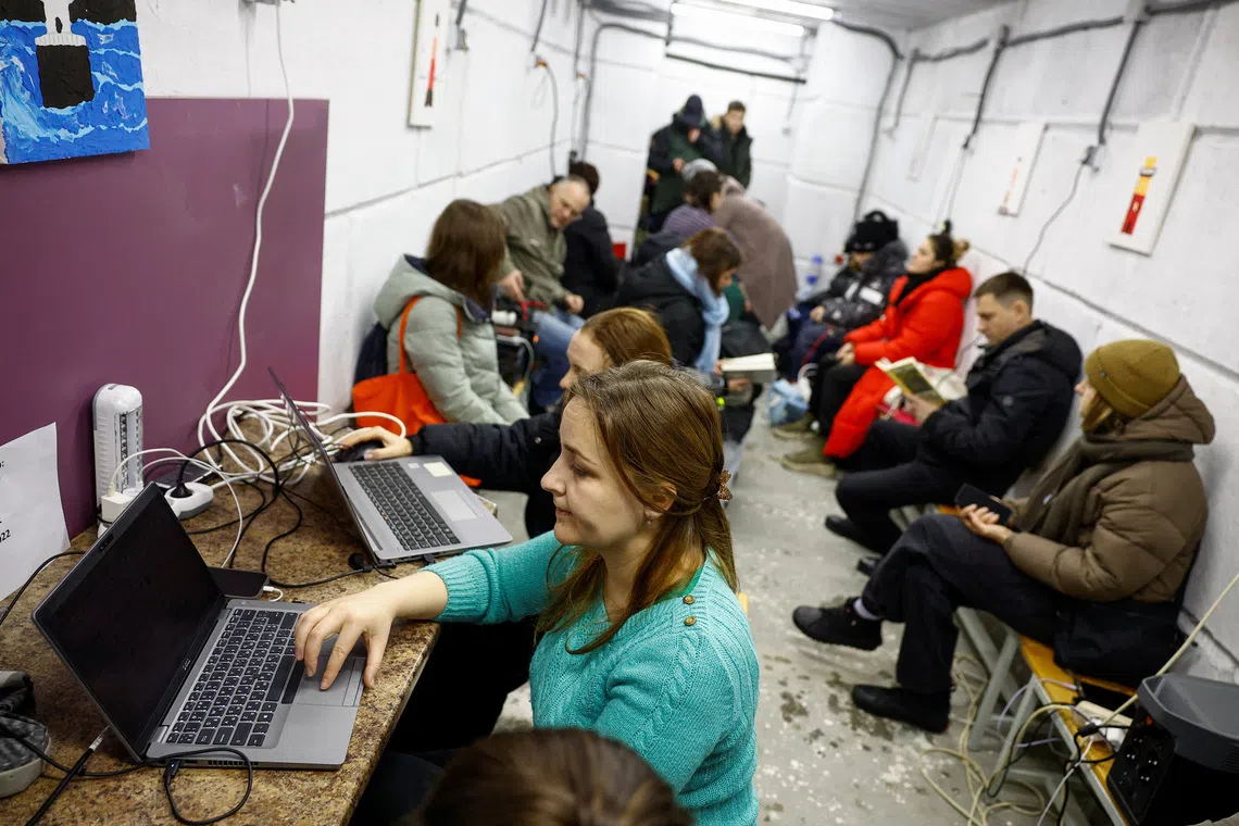 Resident Olena Pozhydaieva works while charging her devices inside a support point, situated in a bomb shelter, during a long power blackout after critical civil infrastructure was hit by Saturday's Russian missile and drone strikes, amid Russia's attack on Ukraine, in the town of Vyshhorod in Kyiv region, Ukraine, December 29, 2025. REUTERS/Valentyn Ogirenko