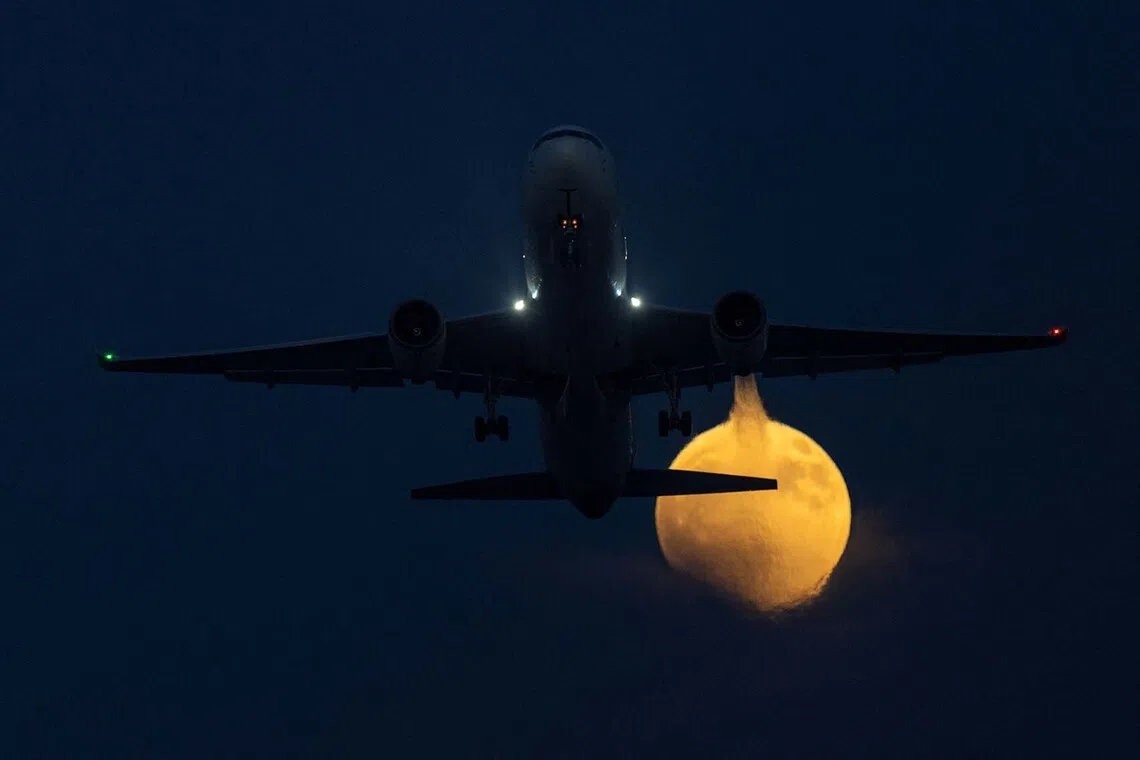 A commercial aircraft takes off during the start of a blood-red lunar eclipse as the moon rises in San Diego, California, U.S., August 27, 2026. REUTERS/Mike Blake TPX IMAGES OF THE DAY