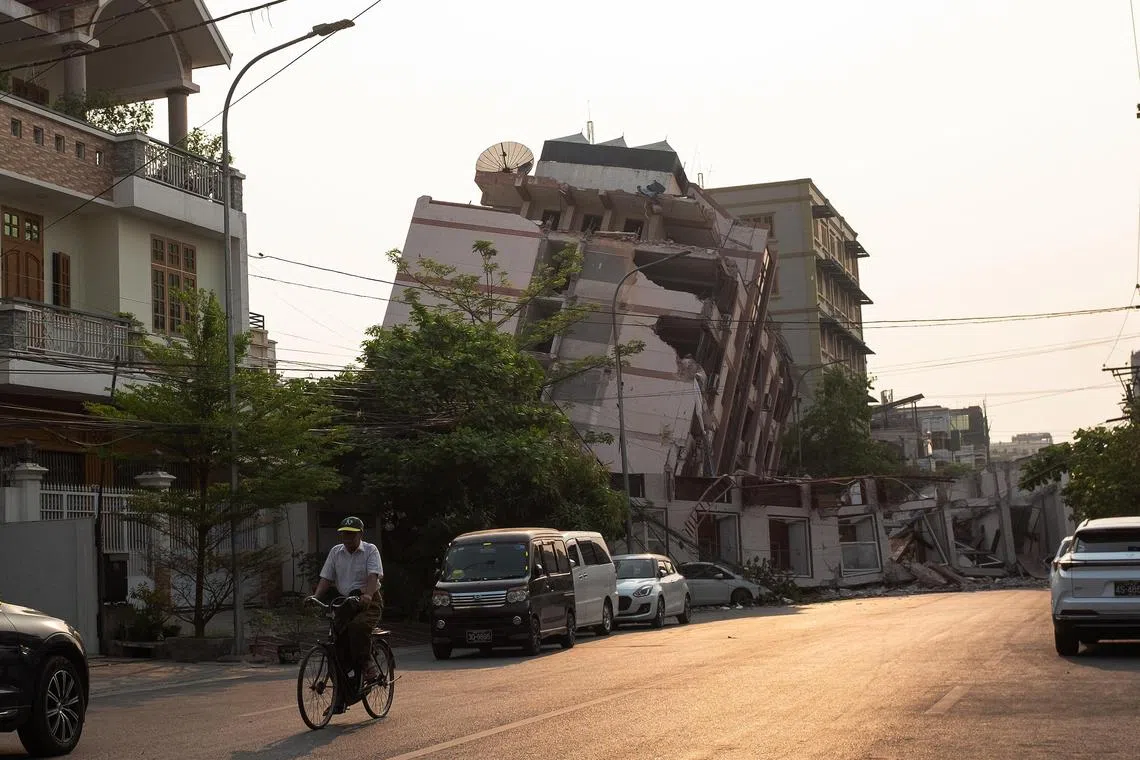 A cyclist rides past a damaged building following an earthquake in Mandalay on March 28.