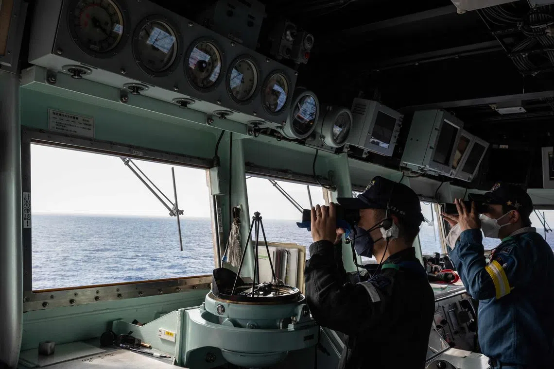 Crew members use binoculars on the bridge of the Japan Maritime Self-Defence Force's Hyuga-class helicopter destroyer "JS Ise", during a three-day maritime exercise between the US and Japan in the Philippine Sea, between Okinawa and Taiwan, on January 31, 2024.