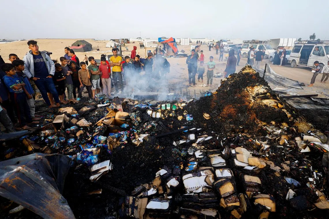 FILE PHOTO: Palestinians look at the damages while searching for food among burnt debris at the site of an Israeli strike on an area designated for displaced people, in Rafah in the southern Gaza Strip, May 27, 2024. REUTERS/Mohammed Salem/File Photo