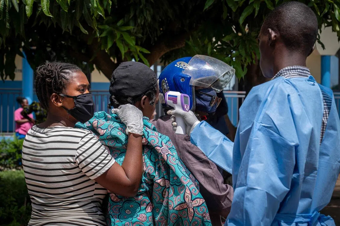 A health worker measures the temperature of a patient suspected of having Ebola as she is transported by motorcycle taxi to a hospital in the Democratic Republic of the Congo.