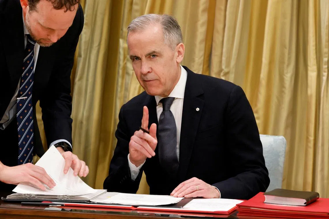 Leader of the Liberal Party of Canada Mark Carney signs documents during his swearing-in ceremony as Canada's next Prime Minister at an event in Ottawa, Ontario, Canada, March 14, 2025. REUTERS/Blair Gable
