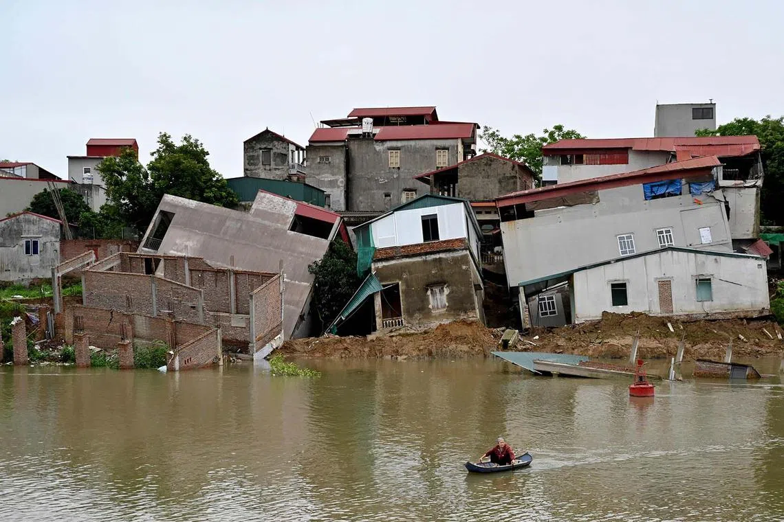 A woman rowing past damaged houses on the banks of Cau River after a landslide in Vietnam's Bac Ninh province on April 8, 2024. 