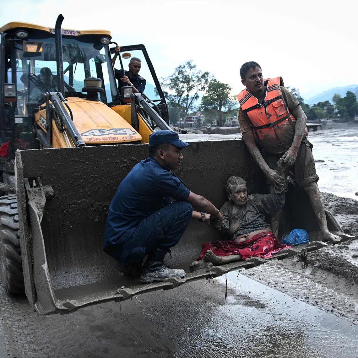 Rescuers use an excavator to transport a flood survivor, following flash floods and a landslide disaster in Devghat, in the Nepal's Nuwakot district on August 26, 2026. A massive flood and landslide disaster on the Nepal-Tibet border killed at least 103 people on August 26, 2026 and left several hundred missing, many of them foreign tourists. Aid workers said entire settlements had been "wiped out". Some 403 tourists -- 341 of them foreigners -- were unaccounted for several hours after the disaster struck, according to the tourism ministry. (Photo by PRAKASH MATHEMA / AFP)