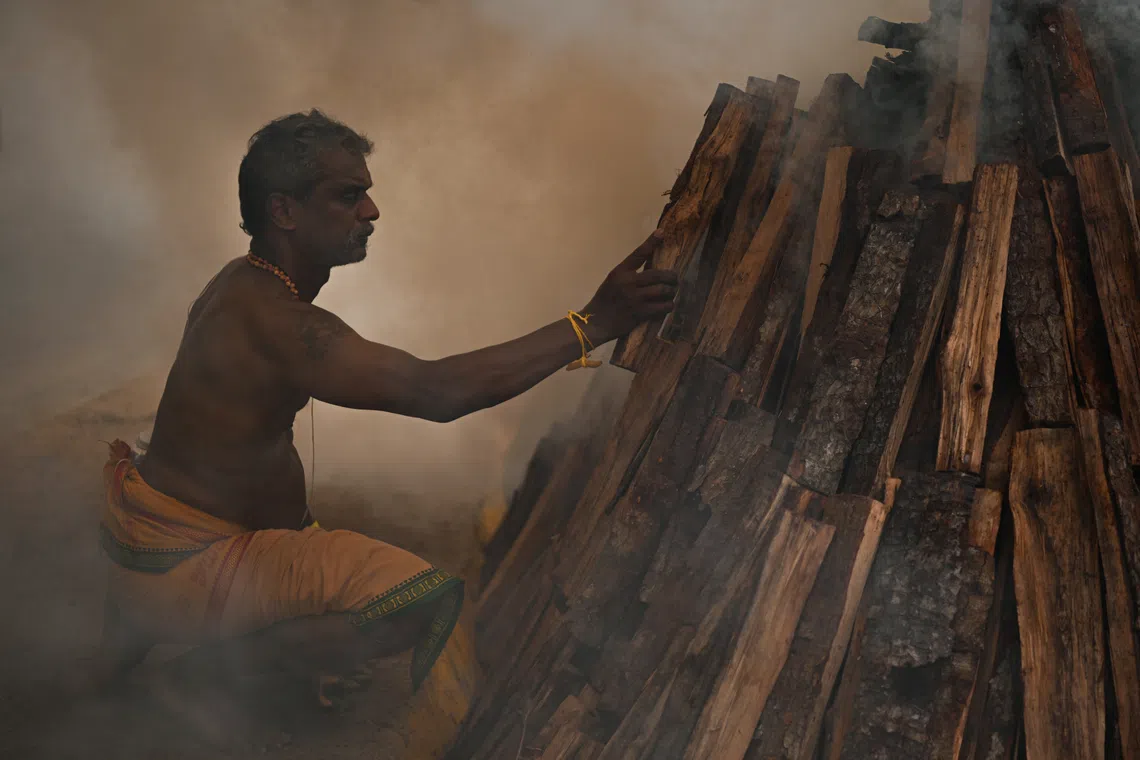 A devotee braving the thick smoke to add more firewood into the pit. 