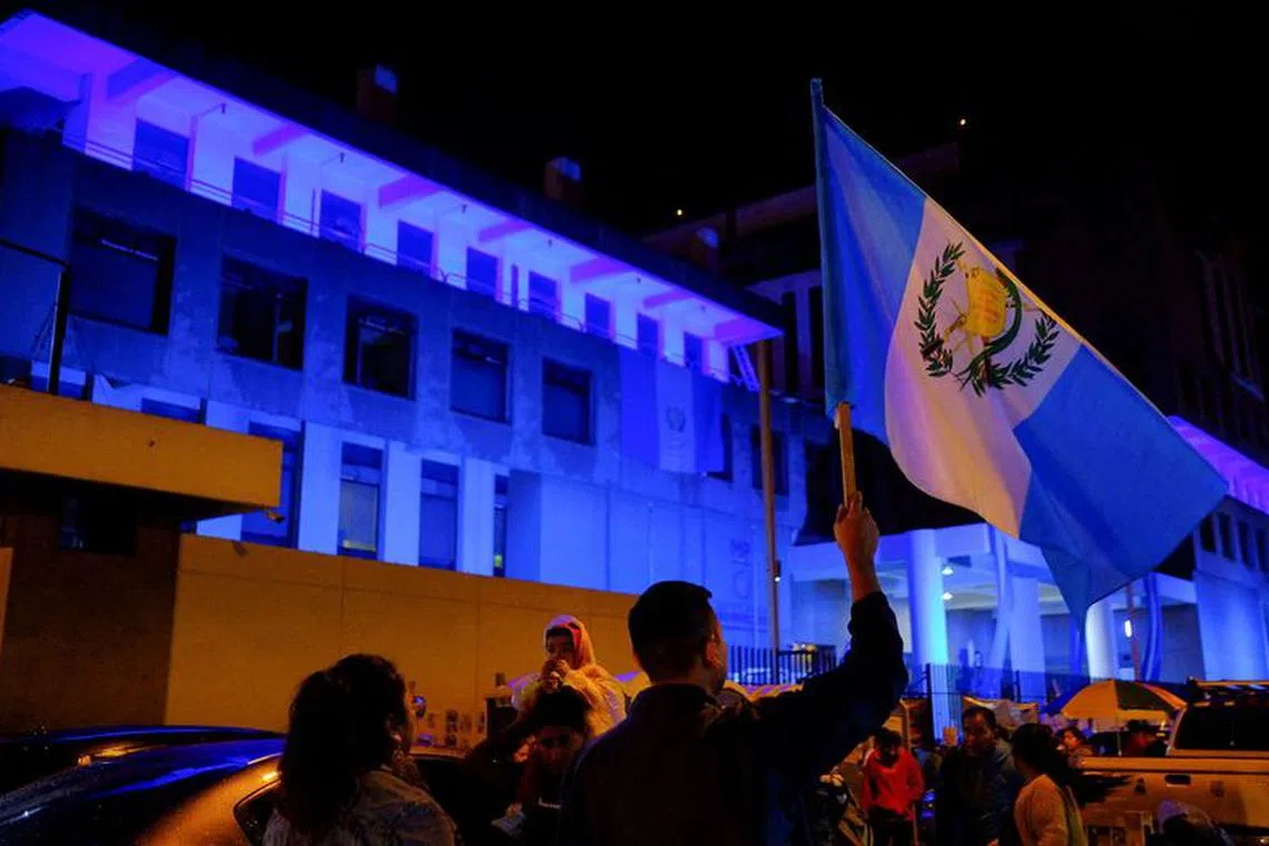 FILE PHOTO: A demonstrator holds up a Guatemalan national flag during a blockade of the Public Ministry building to demand the resignation of powerful senior prosecutors accused of working to undermine President-elect Bernardo Arevalo's ability to take office, in Guatemala City, Guatemala October 6, 2023. REUTERS/Josue Decavele/File Photo