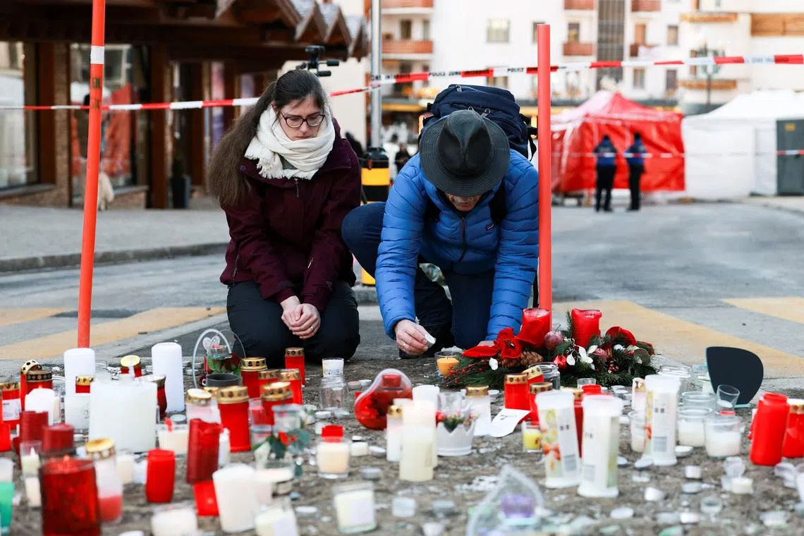 A man lights a candle next to tributes laid for the victims of a New Year’s Eve bar fire, which is said to have claimed around 40 lives, in the Swiss ski resort of Crans-Montana on Jan 2.