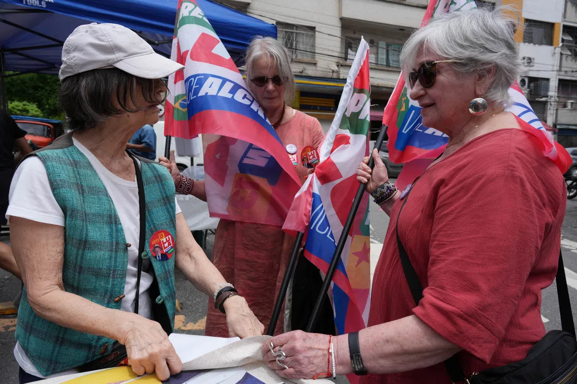 Former political prisoners Rita Sipahi, 88 (R), who shared a cell with former Brazilian President Dilma Rousseff in 1971 during the military dictatorship, Guida Amaral, 75 (C), and Mercia Roberts, 79, hand out campaign material to encourage people to vote for Brazilian President Luiz Inacio Lula da Silva who is seeking re-election, ahead of Brazil's presidential runoff, in Sao Paulo, Brazil, October 15, 2026. REUTERS/Alexandre Meneghini