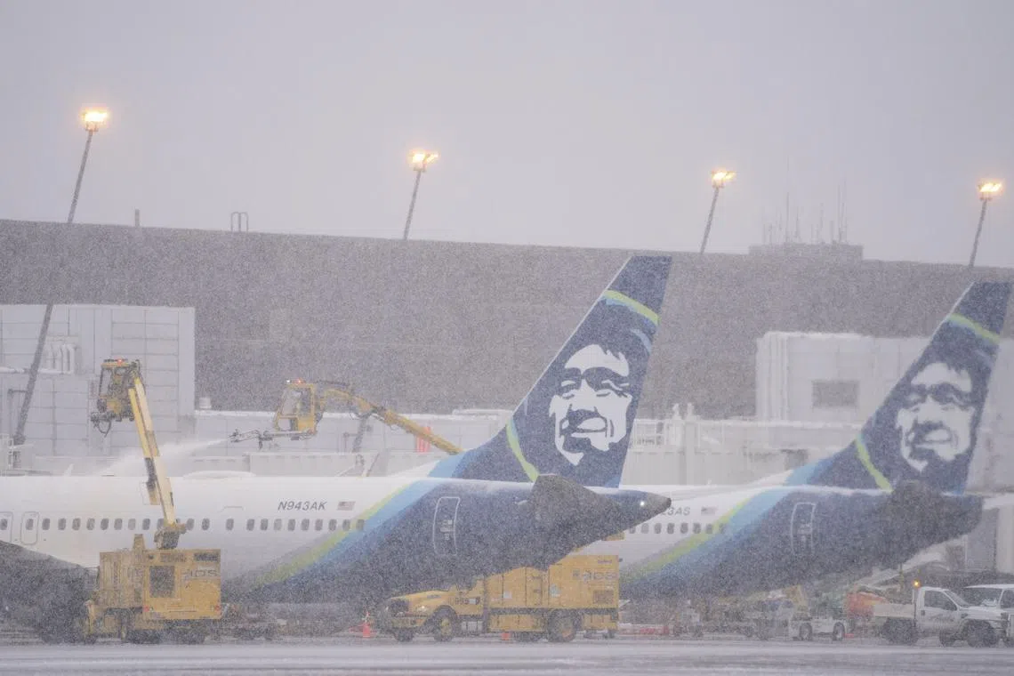 Workers deice an Alaska Airlines plane during a snow storm at in Seattle on Dec 20, 2022.