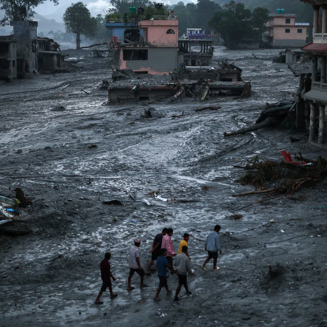People walk next to damaged buildings, following the deadly flash floods and mudslides in Devighat, Nuwakot district, Nepal, September 3, 2026. REUTERS/Athit Perawongmetha