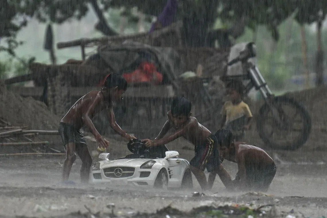 Children play during heavy rainfall in New Delhi on July 9, 2024. (Photo by Arun SANKAR / AFP)