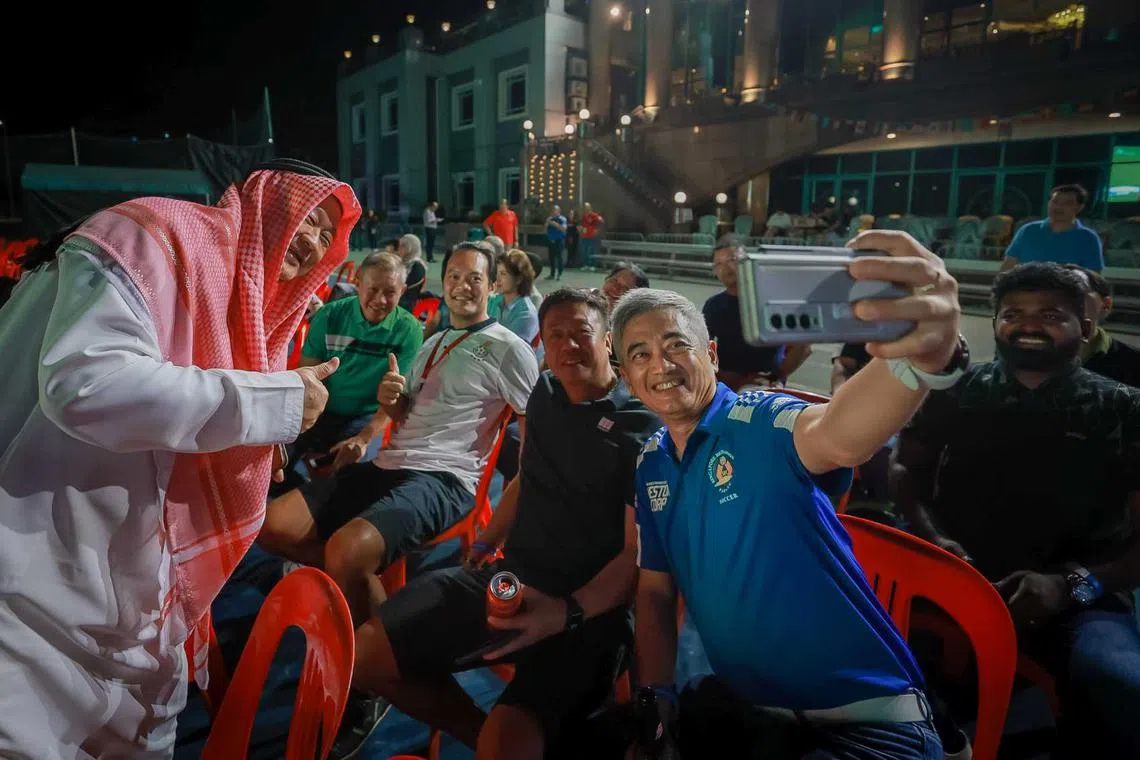 Singapore Recreation Club vice-president Eric Tan (left, in headdress) taking pictures with fans as they watch the screening of the World Cup opening match between Qatar and Ecuador at the Singapore Recreation Club, Nov 20, 2022.