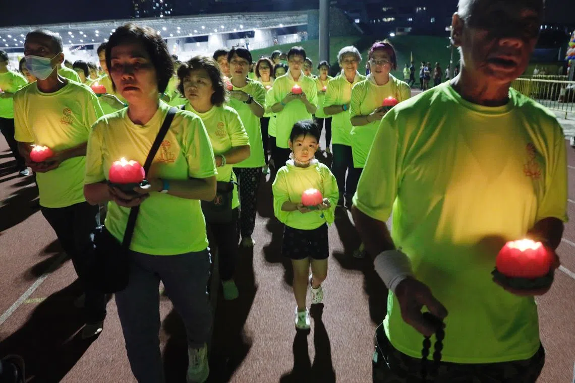 Devotees holding lotus-shaped lamps walking in a procession during Vesak Day celebrations at Bukit Gombak Stadium on Jun 2, 2023. 